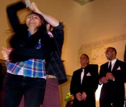 Una mujer bailando y dos hombres esperando que los saquen a bailar. 