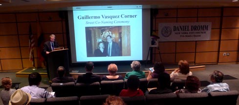El concejal Daniel Dromm hablando en el auditorio del Hospital Elmhurst al lado de una foto de Guilermo Vásquez con Nayibe Núñez-Berger. 