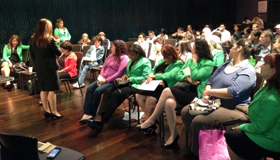 Las representantes de la Cácama de Comercio de Mujeres de Queens, vestidas de verde y participando con el público en el Teatro de Parque Flushing de Queens.