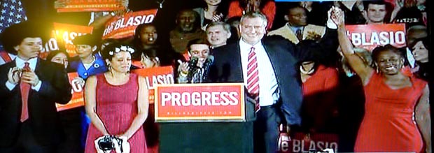 Bill de Blasio sosteniendo la mano de su esposa Chirlane McCray y al lado de sus dos hijos, Dante, con afro, y Chiara, luciendo flores en su cabeza.