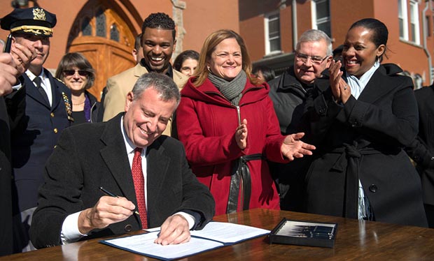 El alcalde Bill de Blasio firmando la ley en compañía de las concejales Melissa Mark-Viverito y Julissa Ferreras. Foto Alcaldía NY.
