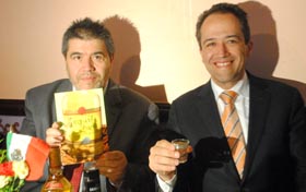 Carlos Velásquez sosteniendo su libro sobre el tequila y en compañía de d