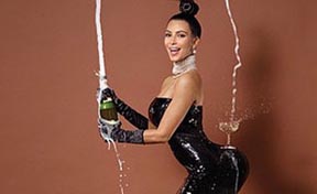Kim Kardashian abriendo una copa de champaña y llenando un vaso que sostiene en sus nalgas. 