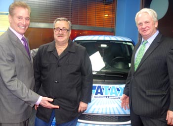 En la nueva sede y frente al carro adornado con el logotipo de ATAX, desde la izquierda, Richard Morris, vicepresidente de ATAX, Barry Knepper, consultor empresarial, y Edward H. Gardner, asesor financiero de Cutter & Company.