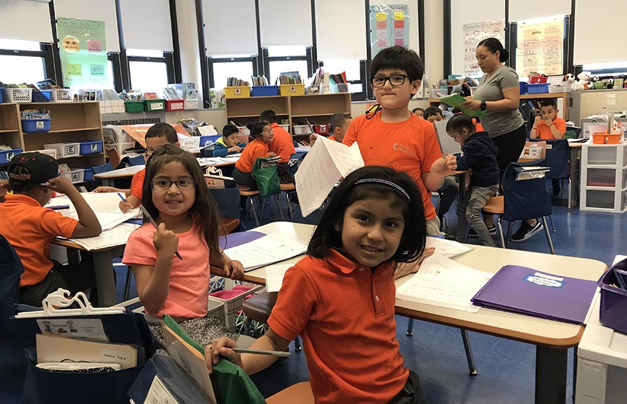 Las niñas Sofía Tapia y Hiydee Chacho en una clase de idioma dual con la profesora Jackie Núñez al fondo.