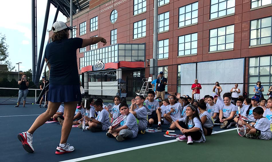 Gigi Fernández hablando con los niños latinos para motivarlos a jugar tenis.