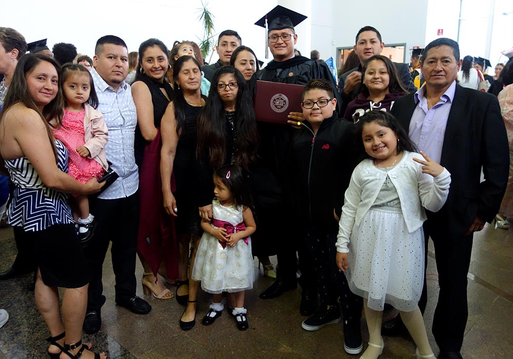 Diego Carpio con toga y birrete y acompañado de su familia en el Vaughn College. 
